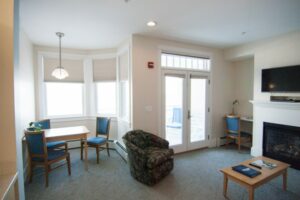 Living room with soft sofas, large windows, table, chair, TV