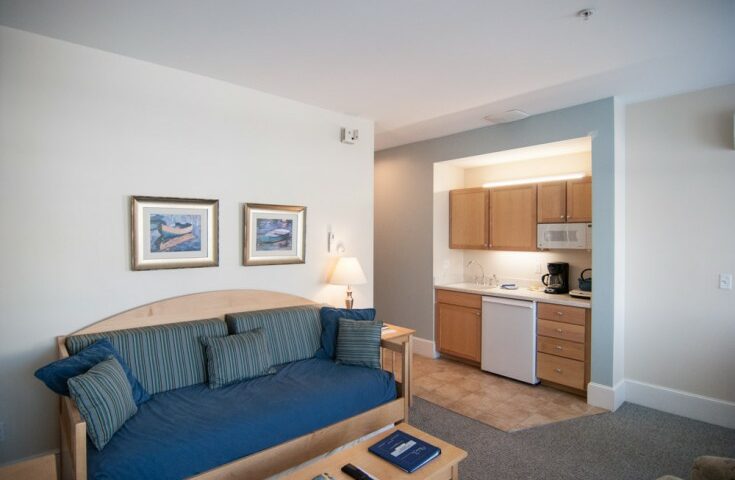 Room with kitchen and soft sofas, large windows, table in Beachmere West