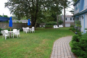 The Bullfrog Cottage's yard with tables and chairs, as well as a grill.