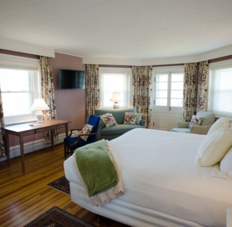 Hotel room with large windows, TV, queen bed and armchair in the Hearthstone House, Maine